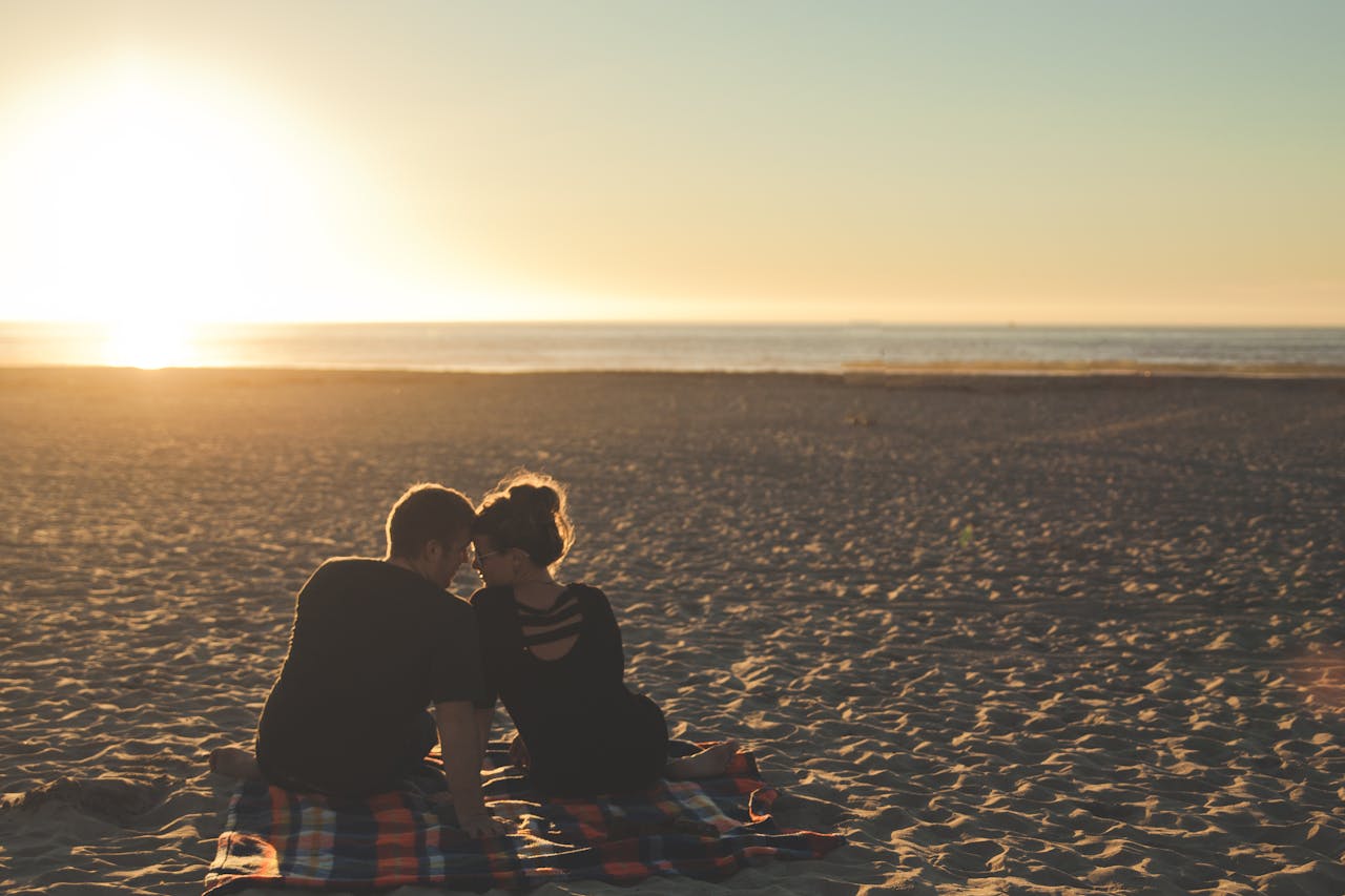 services-03 A couple enjoys sunset together on a sandy beach, capturing a moment of love and togetherness.